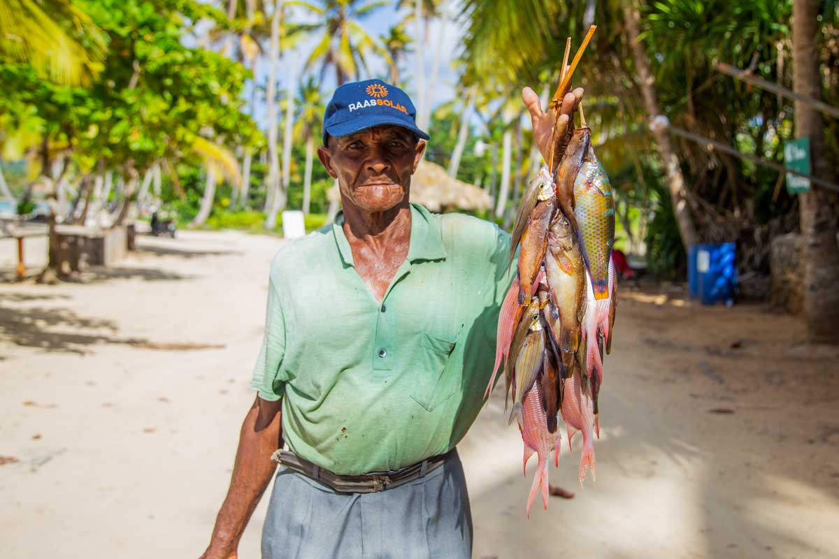 Older Dominican man holding line of caught fish.