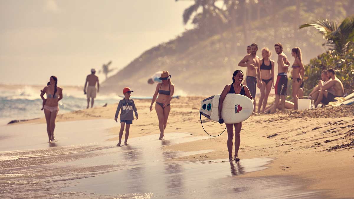 Girl with surfboard walking on shore.