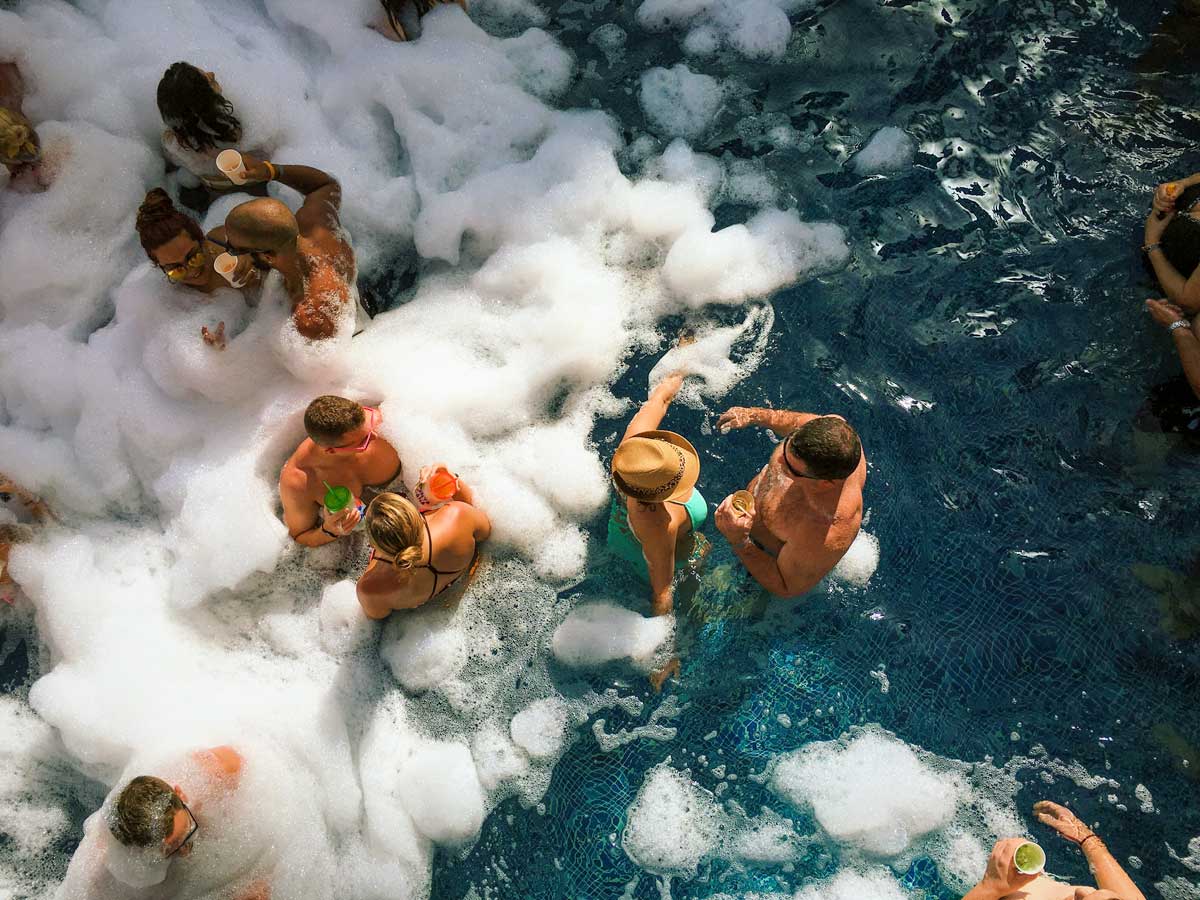 Foamy pool with couples drinking.